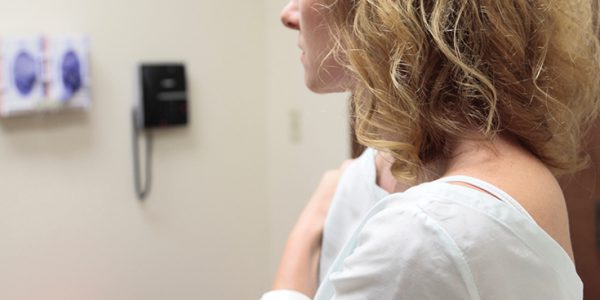 Female patient in gown looking away from the camera in a doctor's office