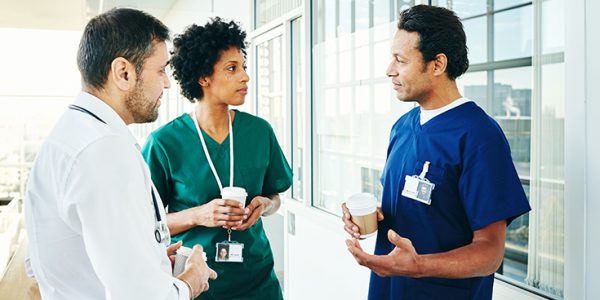 Three healthcare providers conversing in a hallway