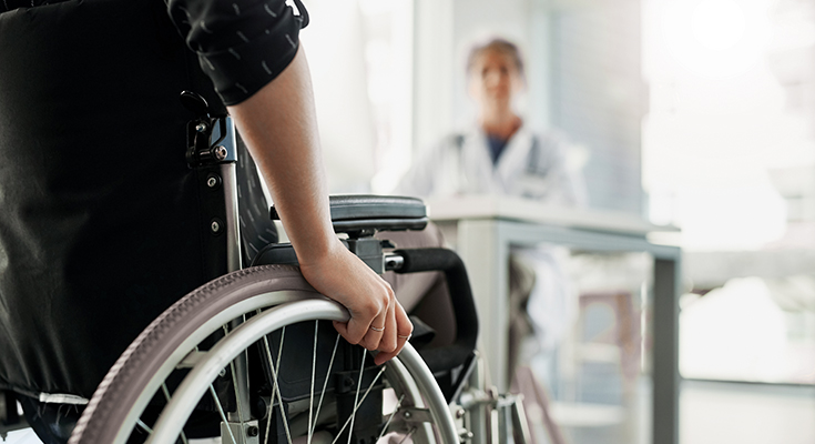 Photo of someone in a wheelchair from behind approaching a physician