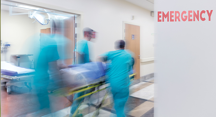 Blurry photo of medical staff pushing gurney through an emergency hallway