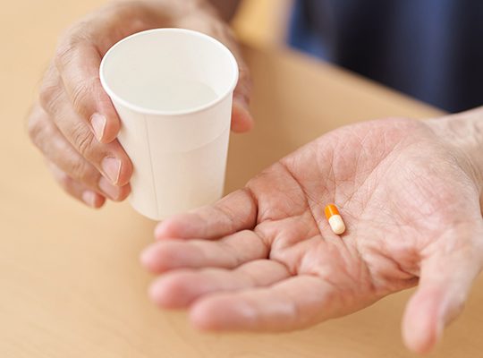 A healthcare worker hands someone a pill and water