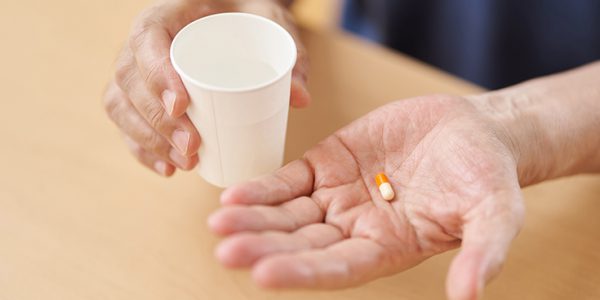 A healthcare worker hands someone a pill and water