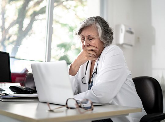 A physician looking at a laptop with concern