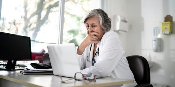 A physician looking at a laptop with concern