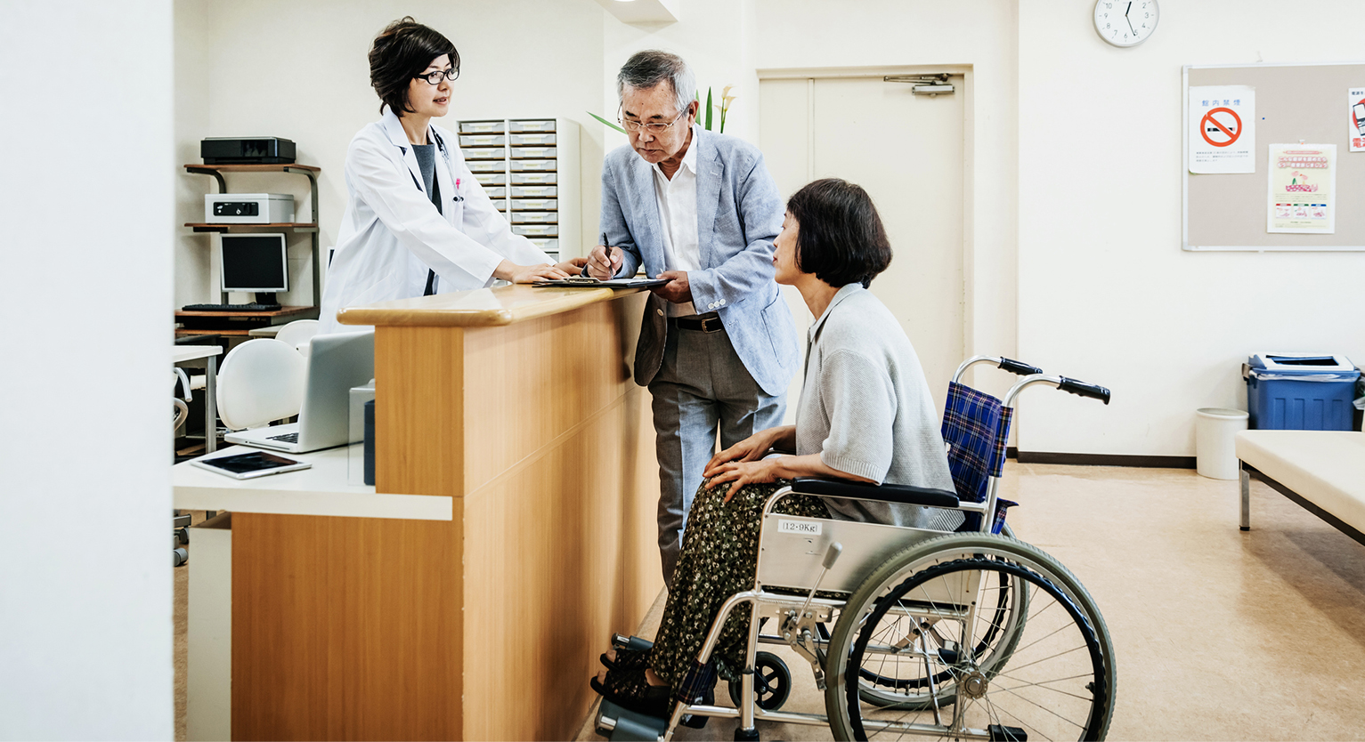 A doctor assists two patients, one of which is in a wheelchair.